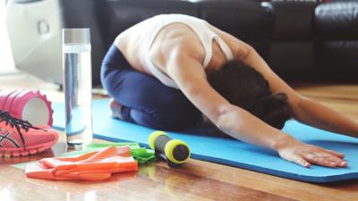 Woman in childs pose on yoga mat with water bottle